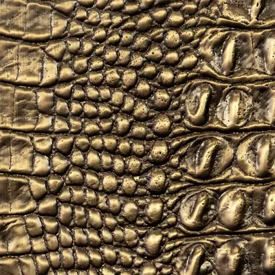 Close-up Crocodile Skin (Aged Cast Brass): greenish-brown metallic surface with a texture that mimics crocodile skin, featuring irregular scales and deep grooves. The finish suggests aged cast brass with a soft sheen.
