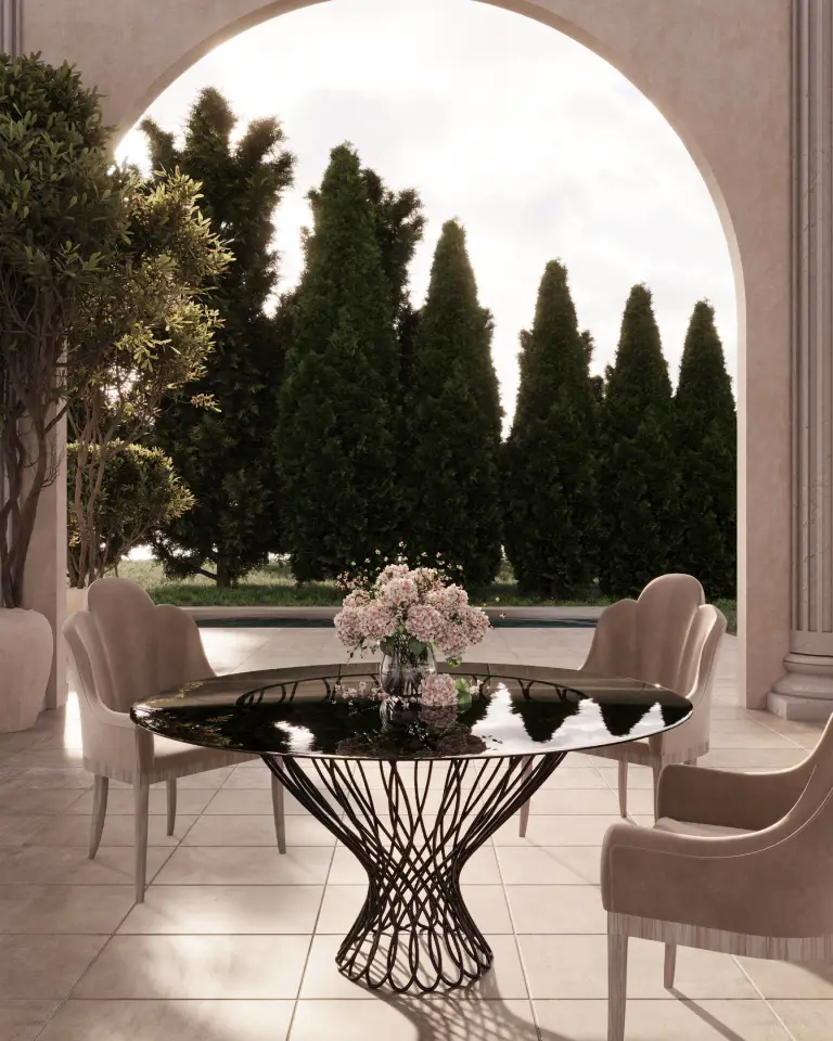 Koket Allure Dining Table featuring a round bronze glass top supported by an interlaced matte gold iron base, set in an elegant dining room with neutral tones.