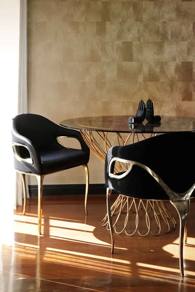 A luxurious dining room features a round Allure Dining Table by Koket and several elegant Chandra Chairs.