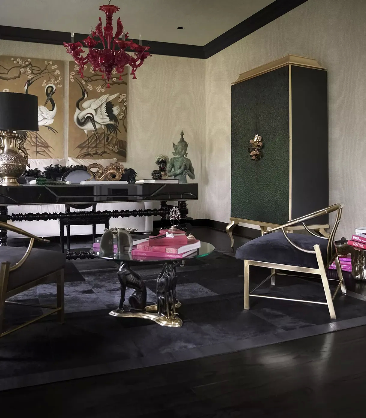 A lavish living room features a Divine Peacock Feather Armoire by Koket, a red chandelier, a black desk, and a glass coffee table.
