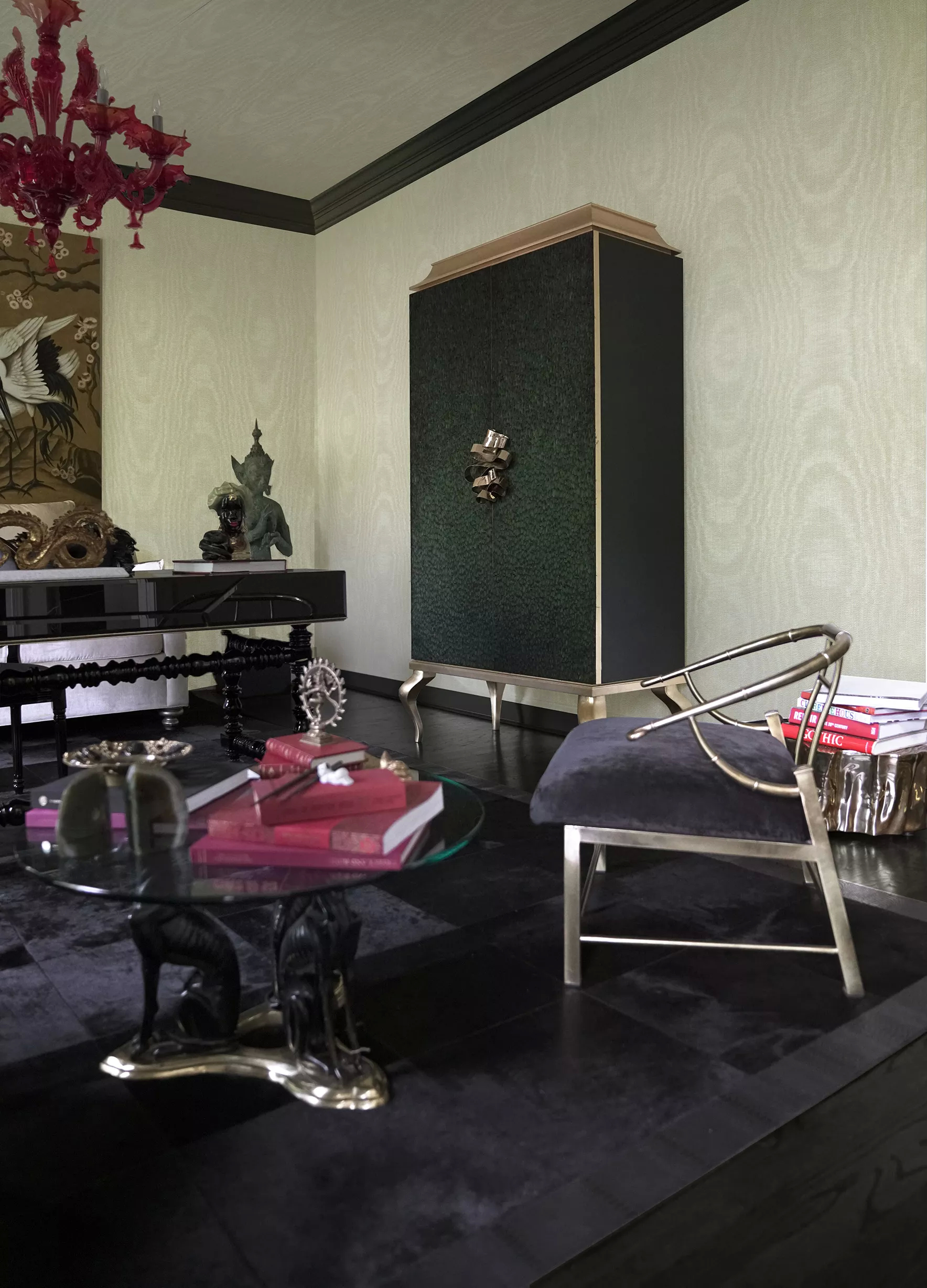 This distinctive home office brims with character, adorned with a variety of exotic decor. A pink chandelier casts a soft glow, while a coffee table with a base resembling dogs adds an original touch. Frames featuring elegant storks hang gracefully, accompanied by other intriguing accessories that enrich the space. To the right, the majestic Divine Armoire stands tall, its natural peacock feathers enhancing the room's enchanting ambiance with their vibrant beauty, perfectly complementing the overall aesthetic.
