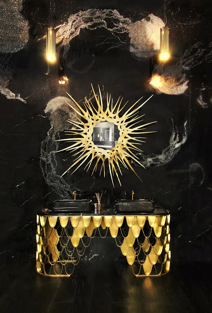 A luxurious bathroom features a Guilt Mirror by Koket above a gold vanity with double sinks, all against a black marble wall.
