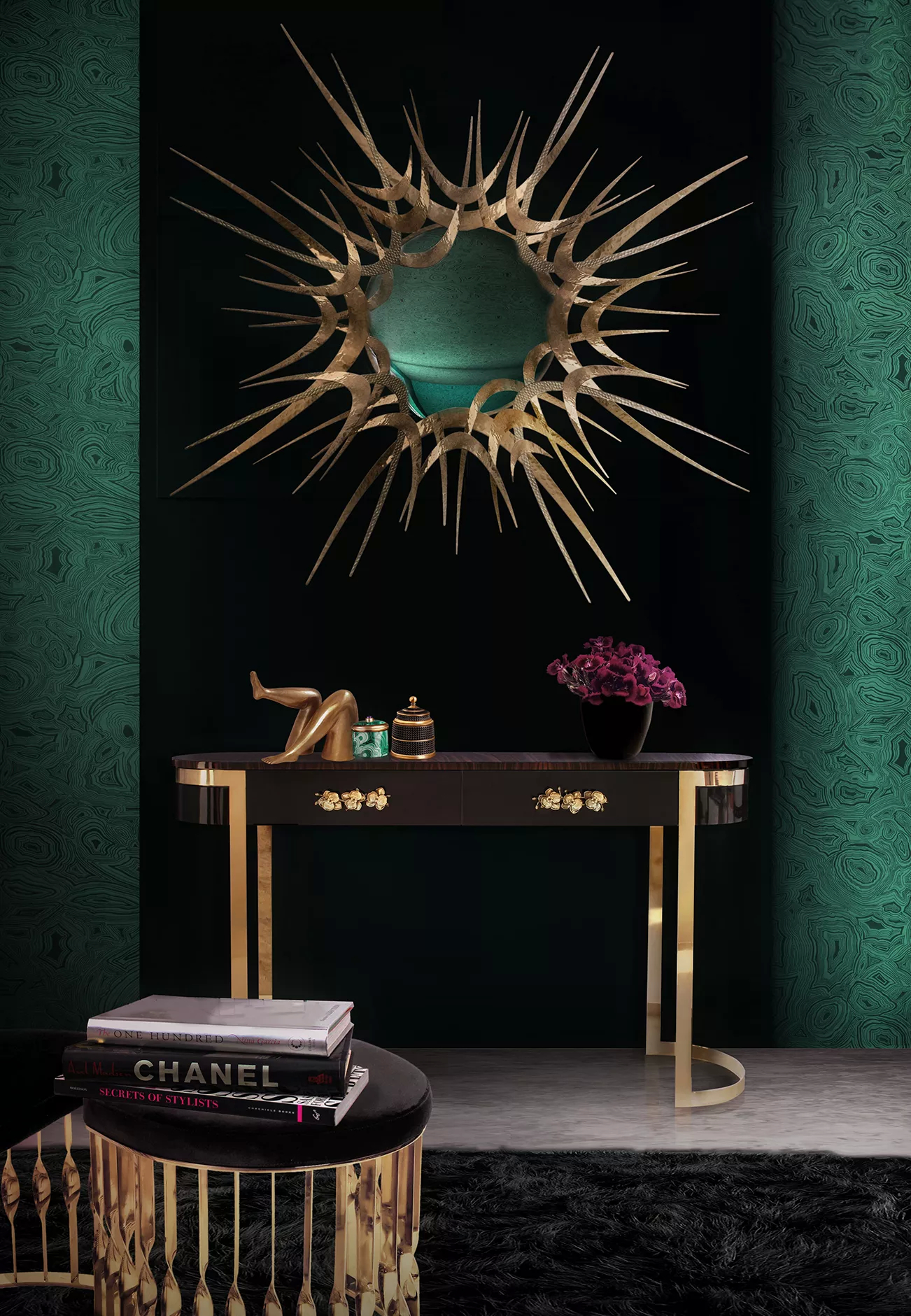 A living room in dark tones such as emerald green and black, featuring furniture in black with golden accents.  In the center of the space, a Guilt Mirror radiates drama, with its frame with spikes. Below the mirror, there is a black Orchidea Console and a Mandy Stool, both adorned with golden accents, such as the handles and structure on the console or the twisted base of the stool.