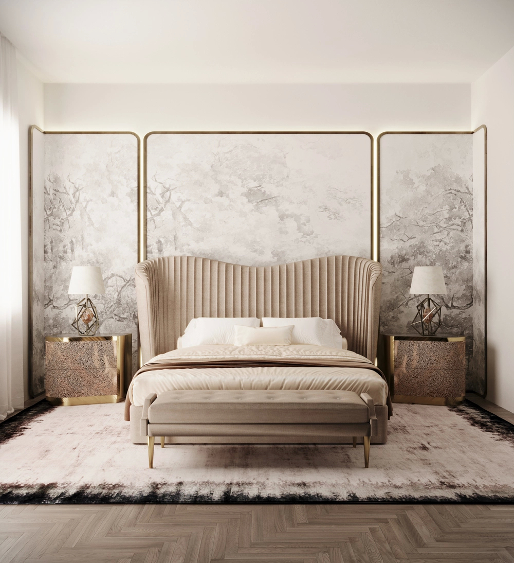Luxurious bedroom with a curvaceous upholstered Kelly Bed by KOKET, flanked by metallic Poem Nightstands and geometric Gem Table Lamps, set against a soft mural wall and finished with the Ignite Bench at the foot of the bed.