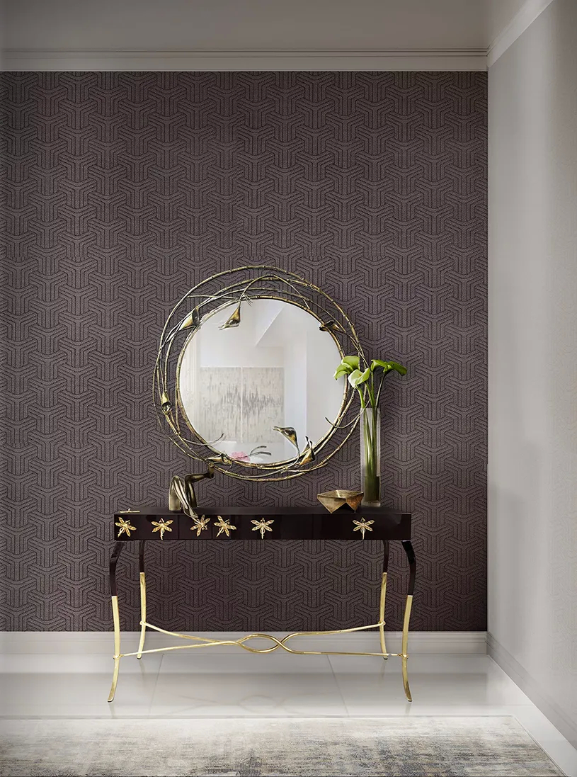 A lavish foyer showcases a Stella Mirror by Koket above a gold and black Luridae Console, against a white paneled wall.