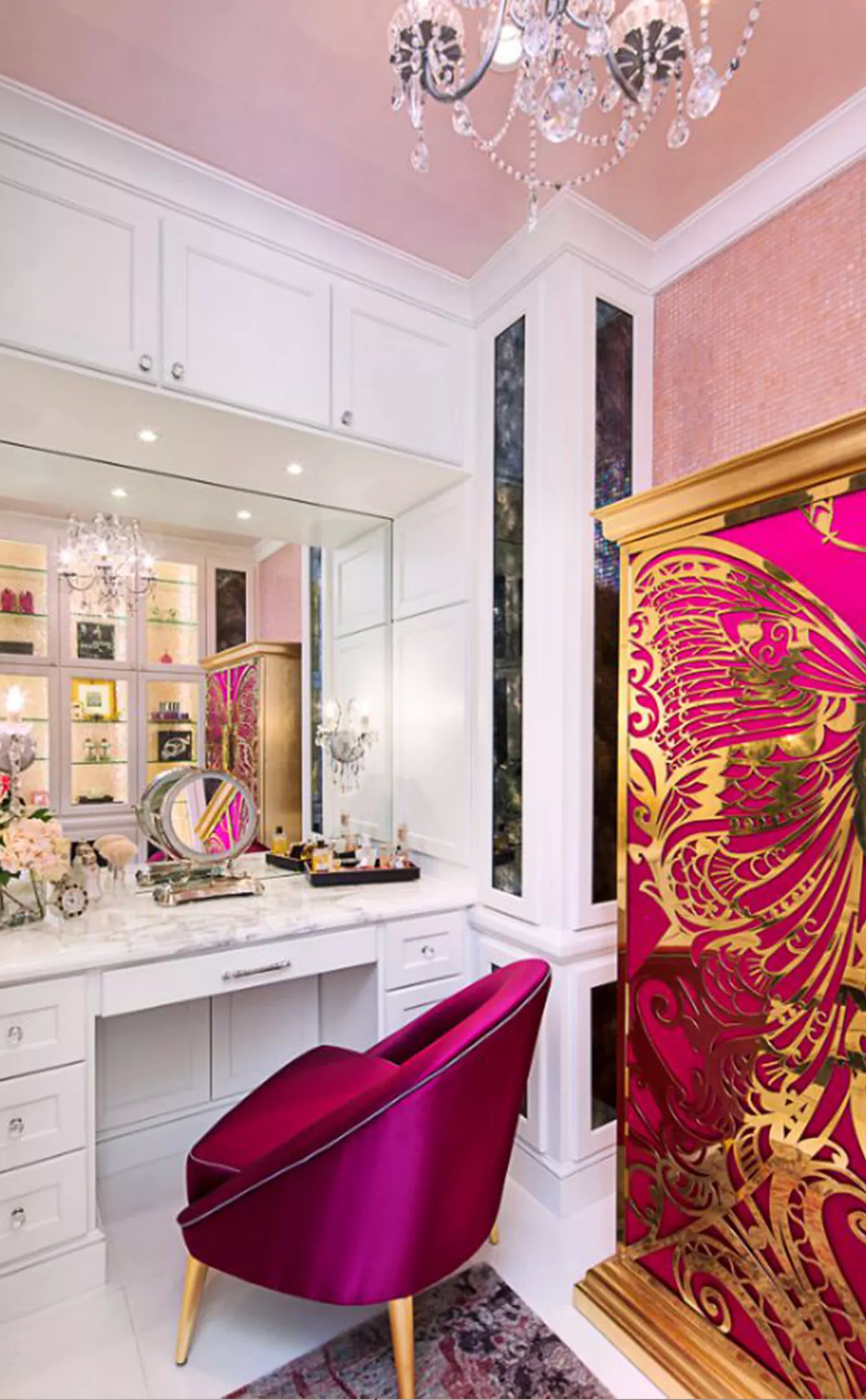 A space full of character, in hues of white and pink. The focal point of the space is the fuchsia Mademoiselle Armoire, with its intricate golden design reminiscent of a butterfly, complemented by the fuchsia chair. Behind, there is a white dressing table, balancing the bright colors.