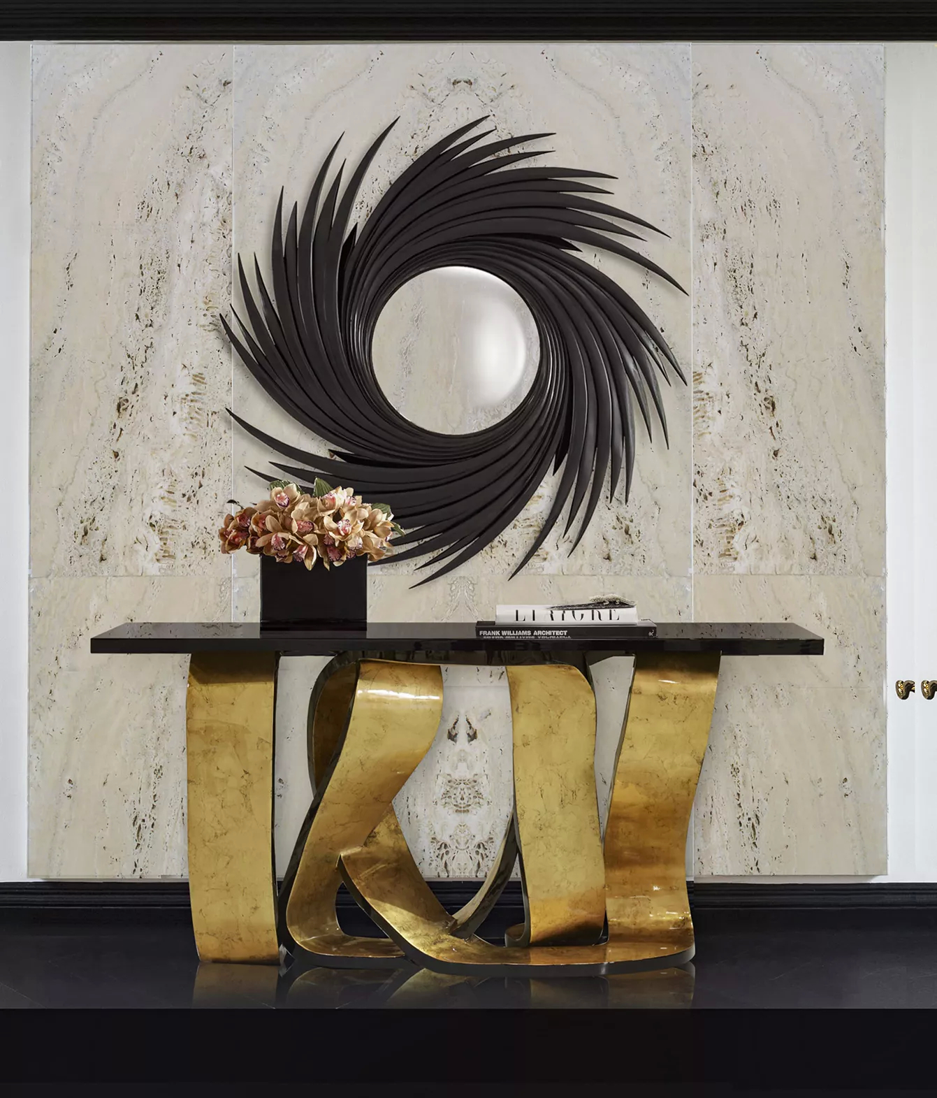 An entryway with a luxurious Ribbon Broken Gold Leaf Console, with a distinctive golden base, characterized by its twists and turns, and a black tabletop. Above the console, there is a mirror with a black frame.
