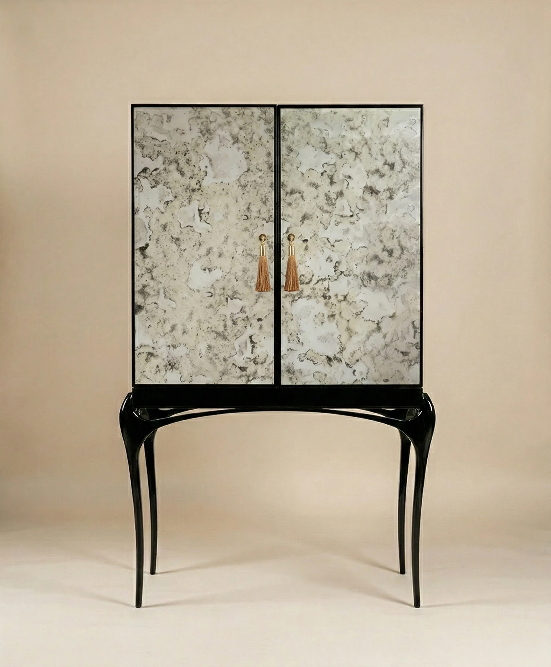 Luxury cabinet with marble-patterned doors, black sculptural legs, and gold tassel handles on a neutral background.