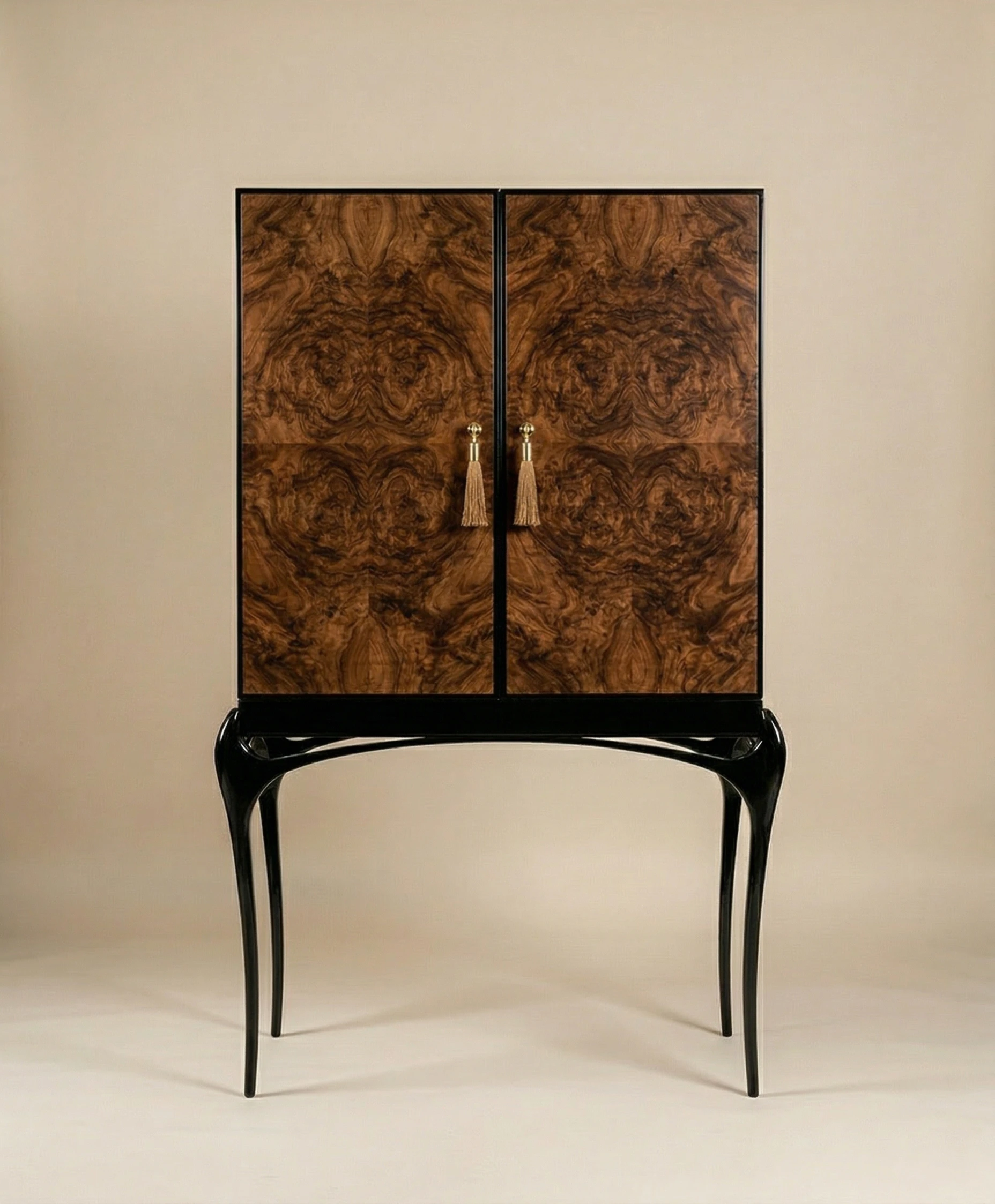 Luxury cabinet with rich wood veneer doors, sculptural black legs, and gold tassel handles on a neutral background.