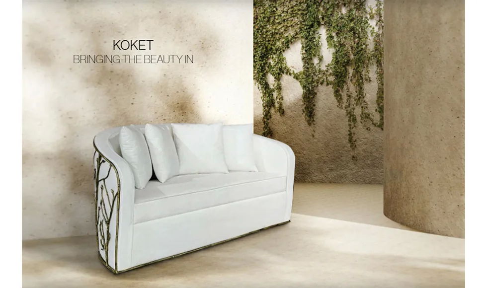Elevated press clipping featuring Koket's Enchanted Sofa, a white sofa with gold detailing, in a room with vines.