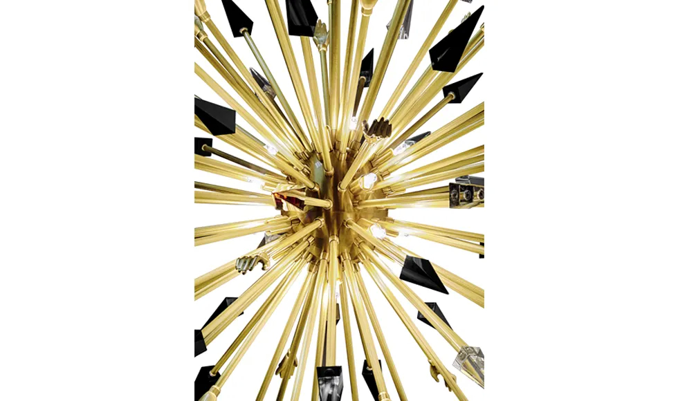 KOKET Outburst Chandelier. Polished brass starburst with black accents and crystal details, featured in Lush Magazine as a bold luxury lighting statement.