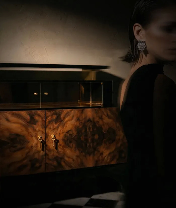 Walnut burl cabinet with brass key handles beside a woman in black, from KOKET's The Women of Art Deco.