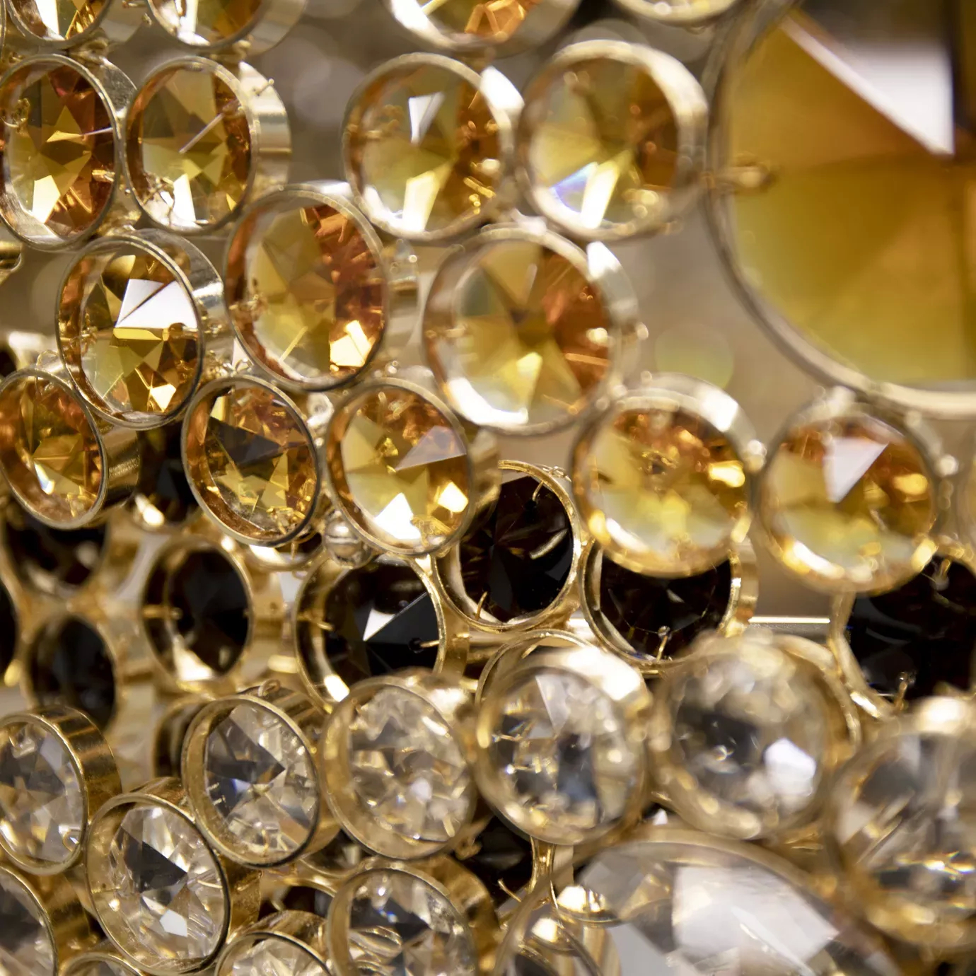 A detailed close-up of the Trinity Chandelier showcasing its sparkling gold, clear, and dark crystals.