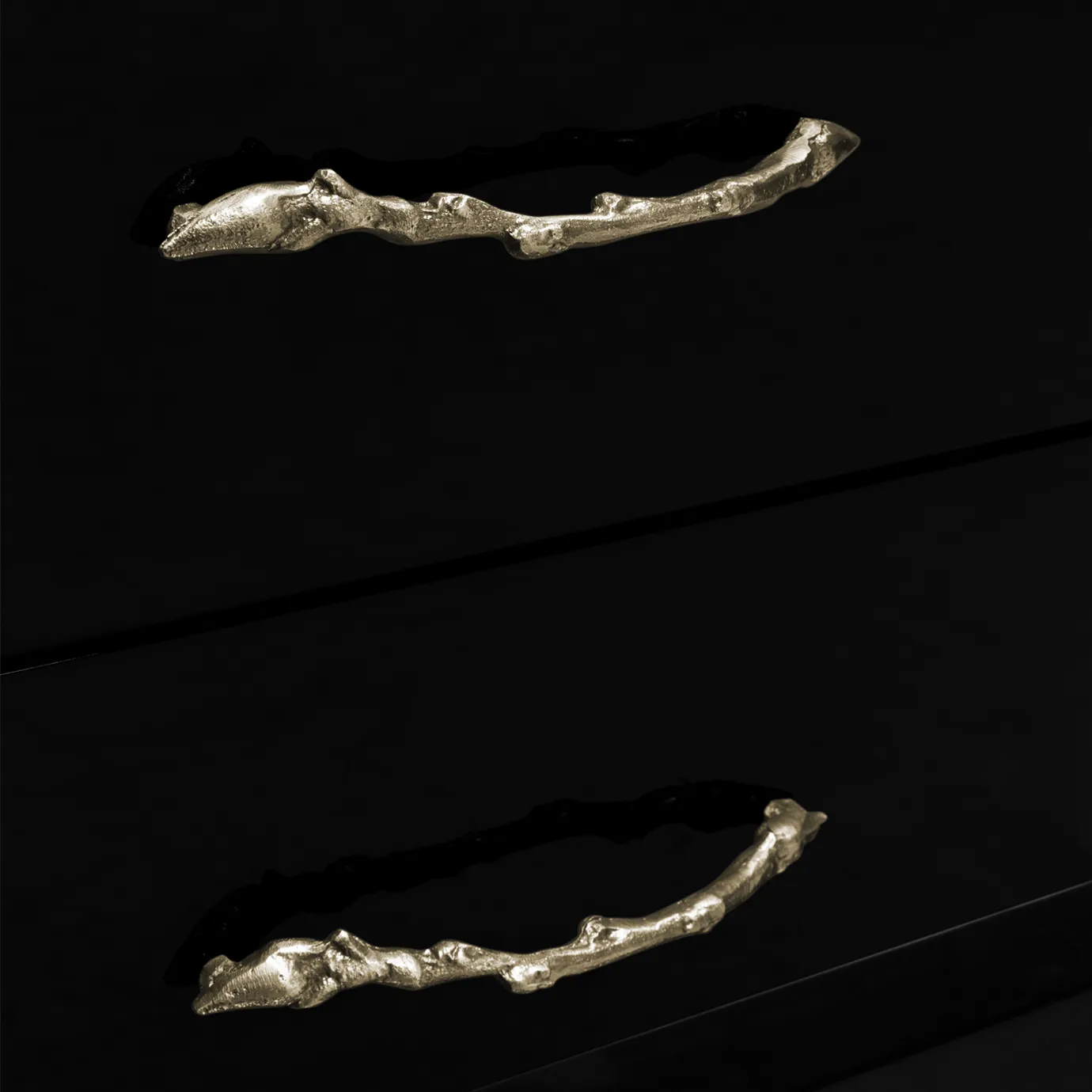 Close look on the drawers handles, resembling golden stems, contrasting with the black lacquer.