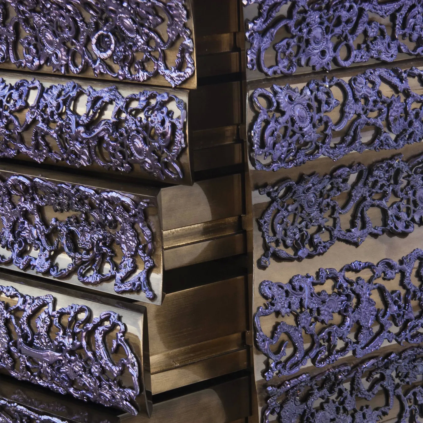 Angled view of gold chest showing side of drawers with hammered texture and crochet-style pattern.