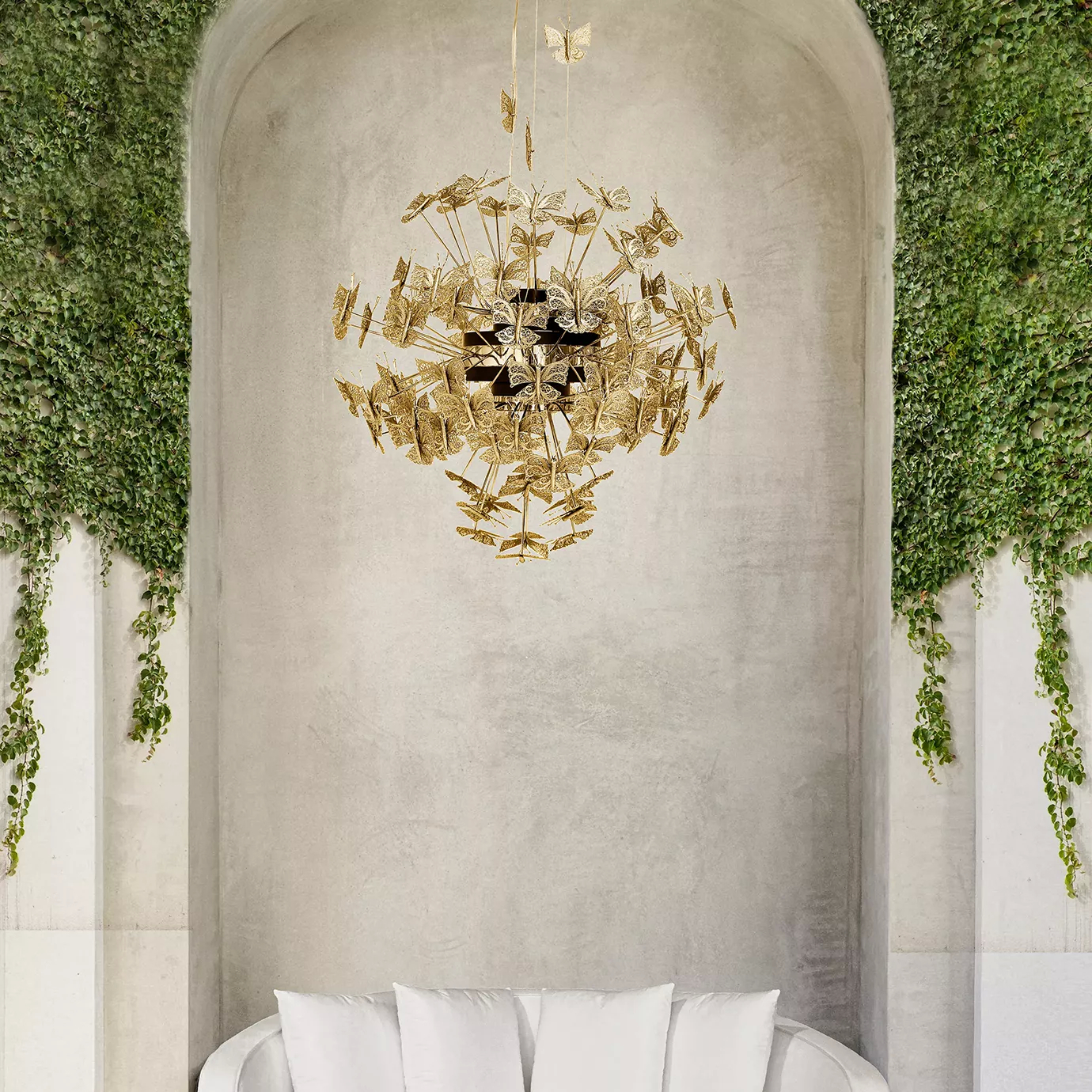 A grand Nymph Chandelier, adorned with numerous gold butterflies, hangs in a light-filled alcove with lush green ivy.