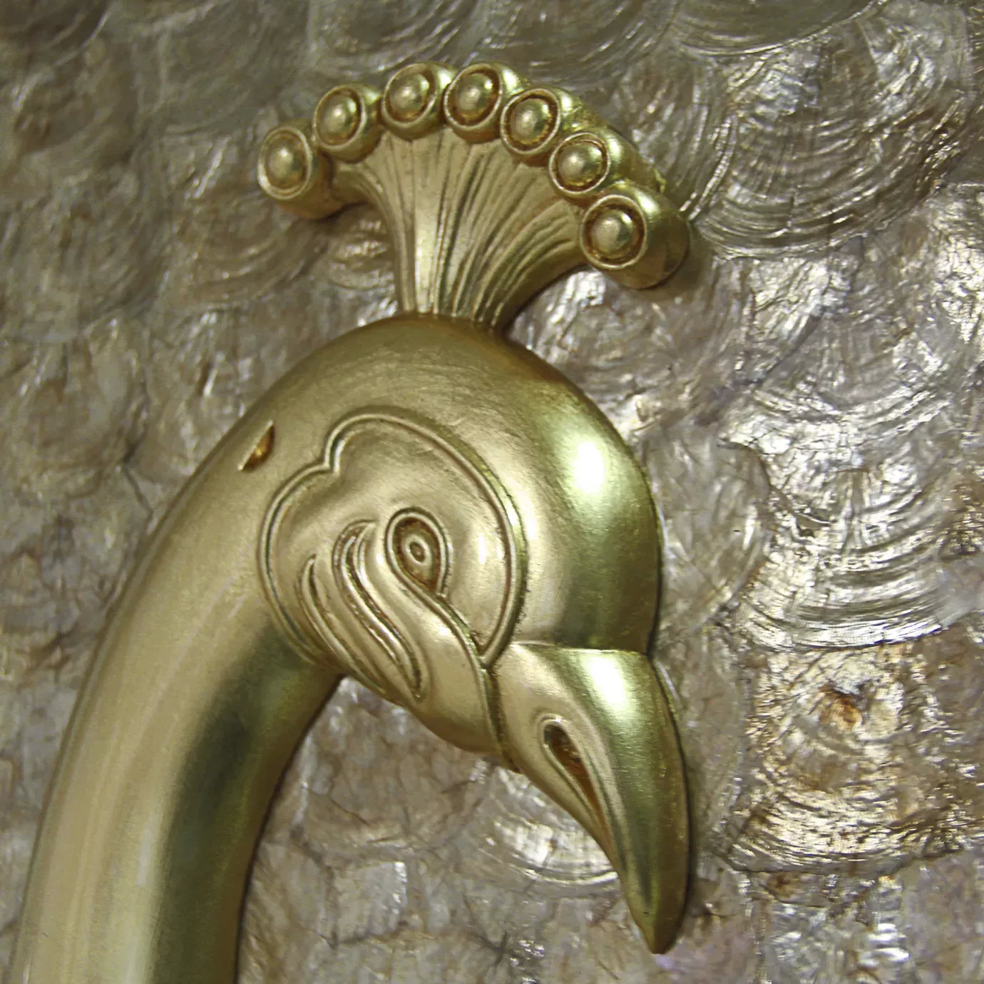 A detailed close-up of the Camilia Mother of Pearl Armoire, showcasing the exquisite gold peacock head design.