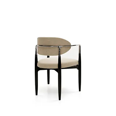 Side view of the Nahéma Chair, showcasing the black structure, creamy upholstery and the silver hand-shaped detail on the backrest.