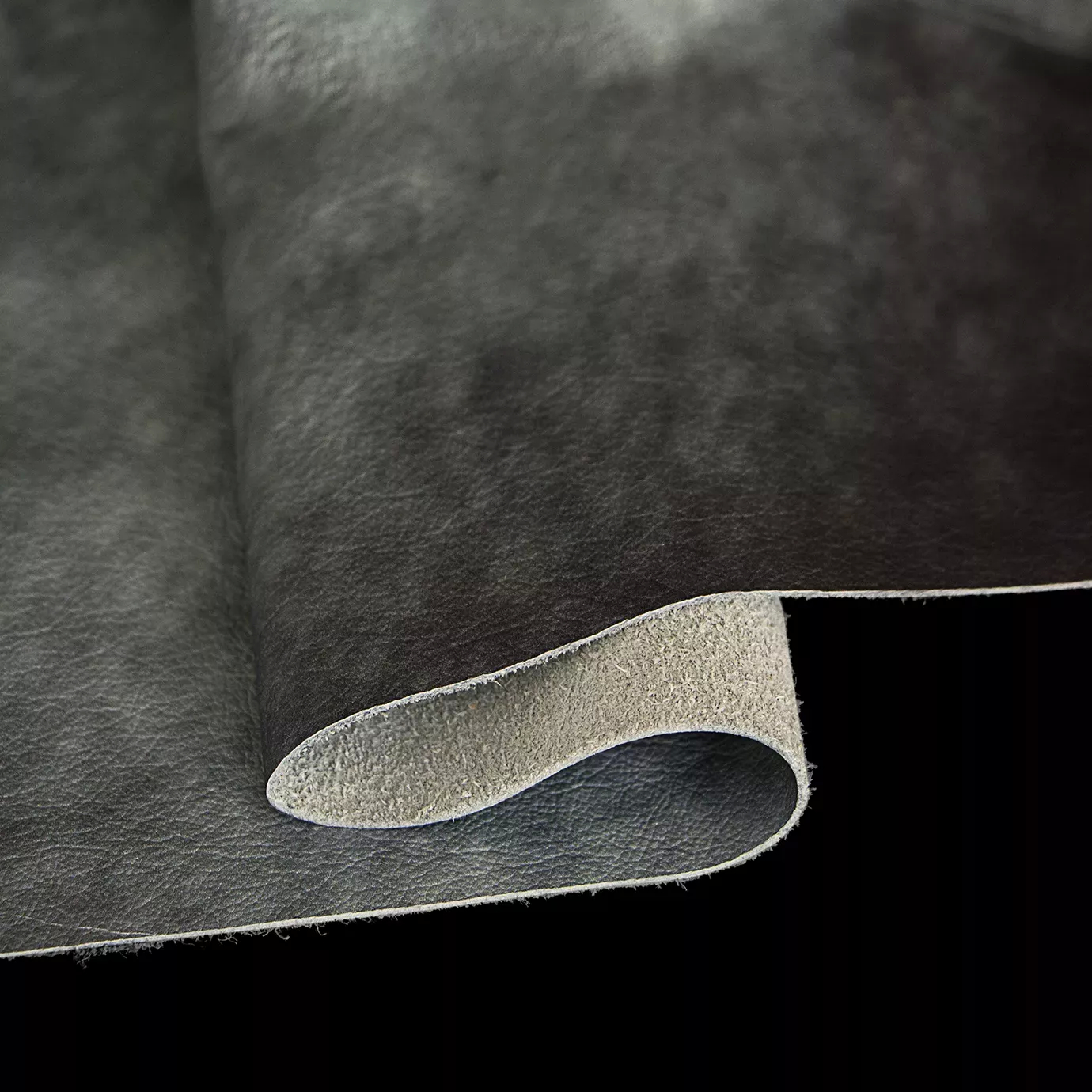 Elegant close-up of a Watermark Aqua Leather swatch in a soft aquatic tone with a subtle watermark effect, revealing its thickness and raw underside, featuring a natural grain texture that gives it depth and a supple touch, evoking a feeling of freshness and organic elegance.