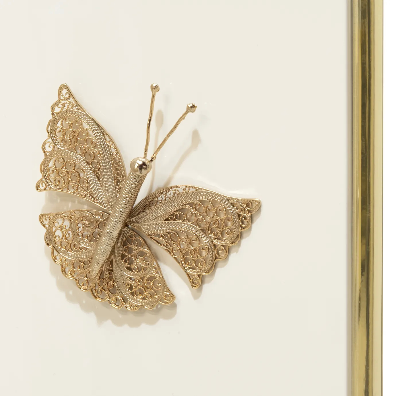 Detailed image of two gold butterflies on the KOKET Euphoria Screen’s cream lacquered panels, connected by golden hinges.