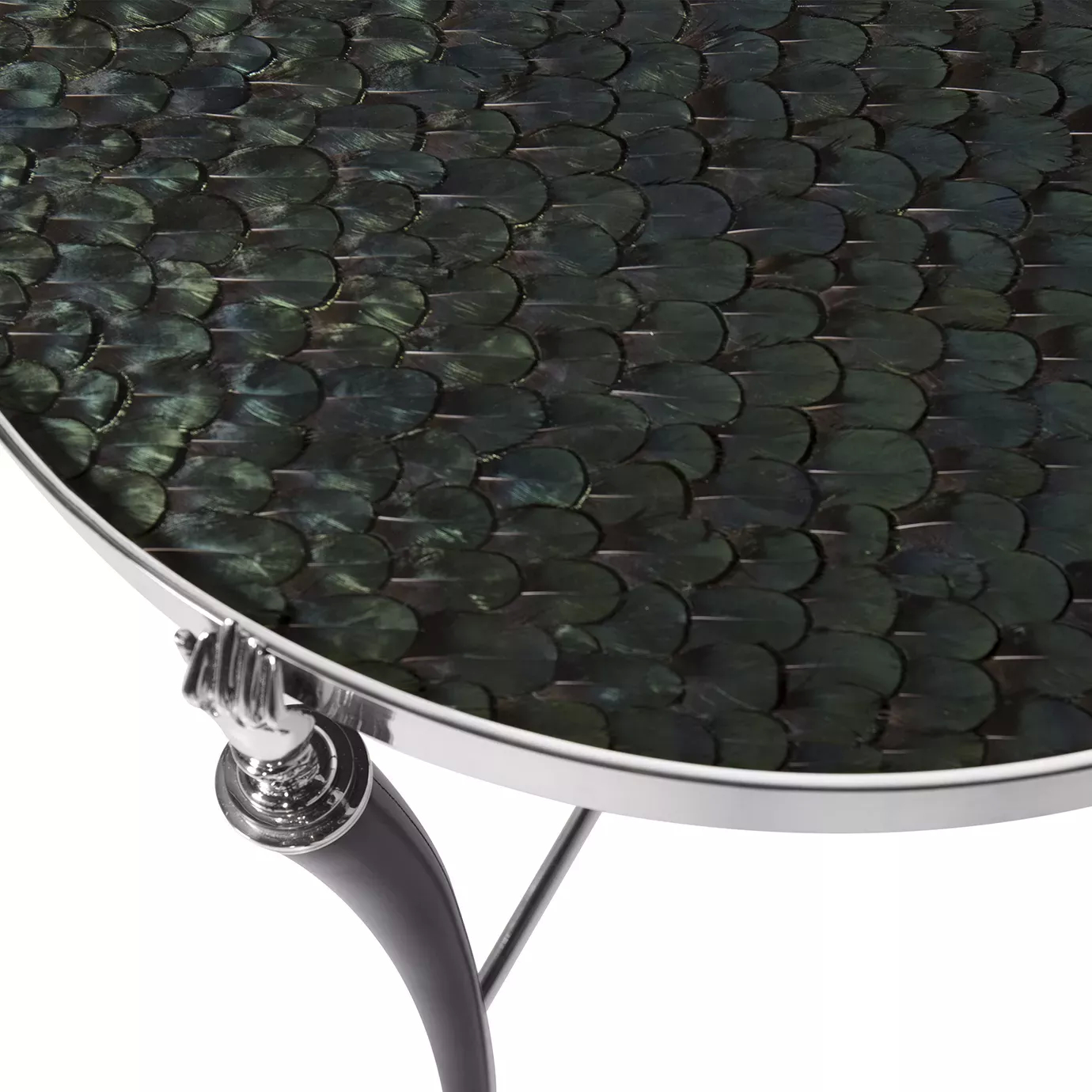 Close-up of the Gisele Side Table, featuring a dark, iridescent peacock feather patterned top, a shiny nickel rim, and a detailed hand-shaped leg joint.