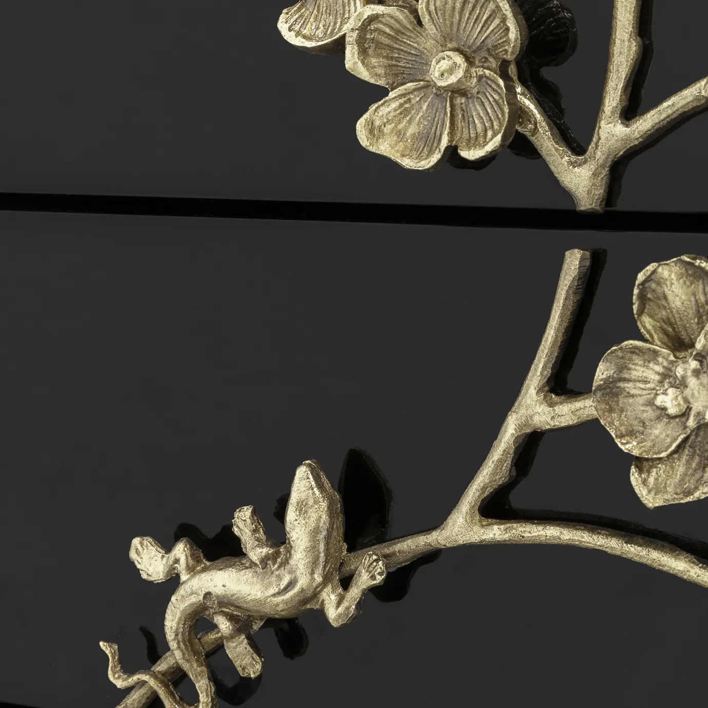 Close-up of the Spellbound Nightstand, focusing on the intricate golden lizard detail amidst the ornate floral design on the glossy black lacquer.