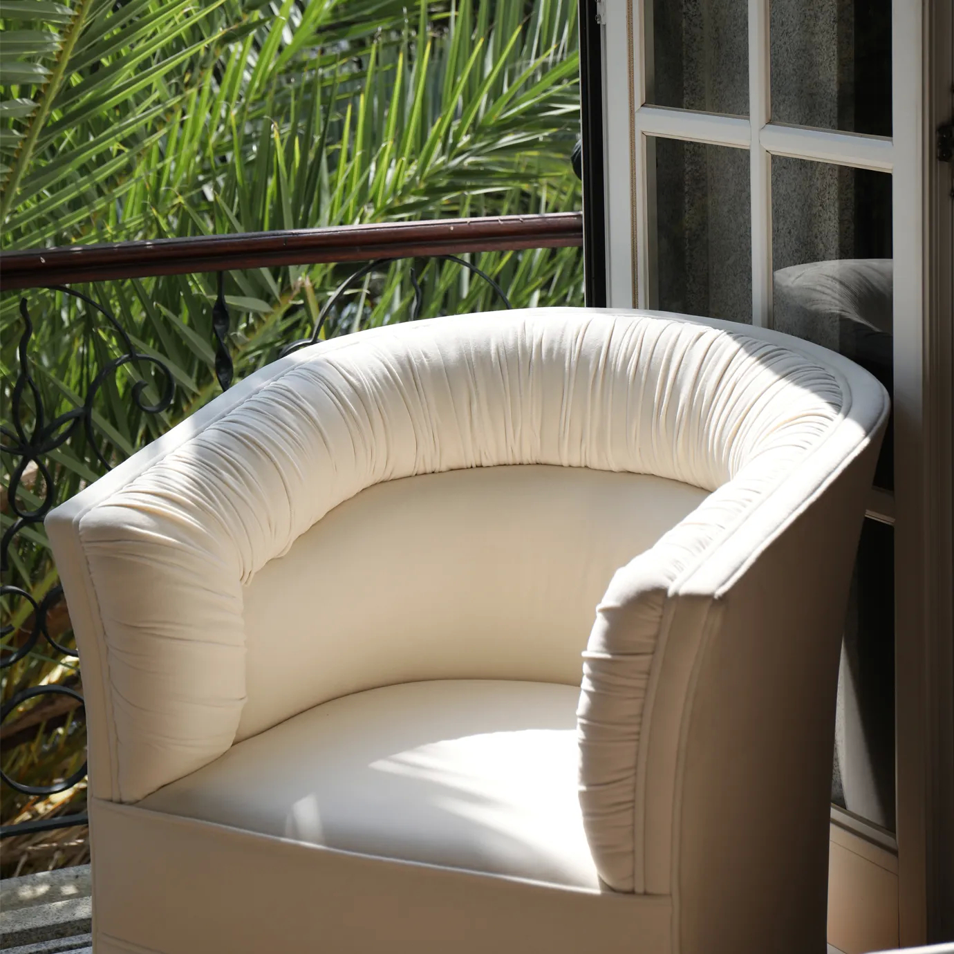 Lovely Armchair near a window: The plush, light-colored armchair sits bathed in sunlight, with a glimpse of greenery outside.