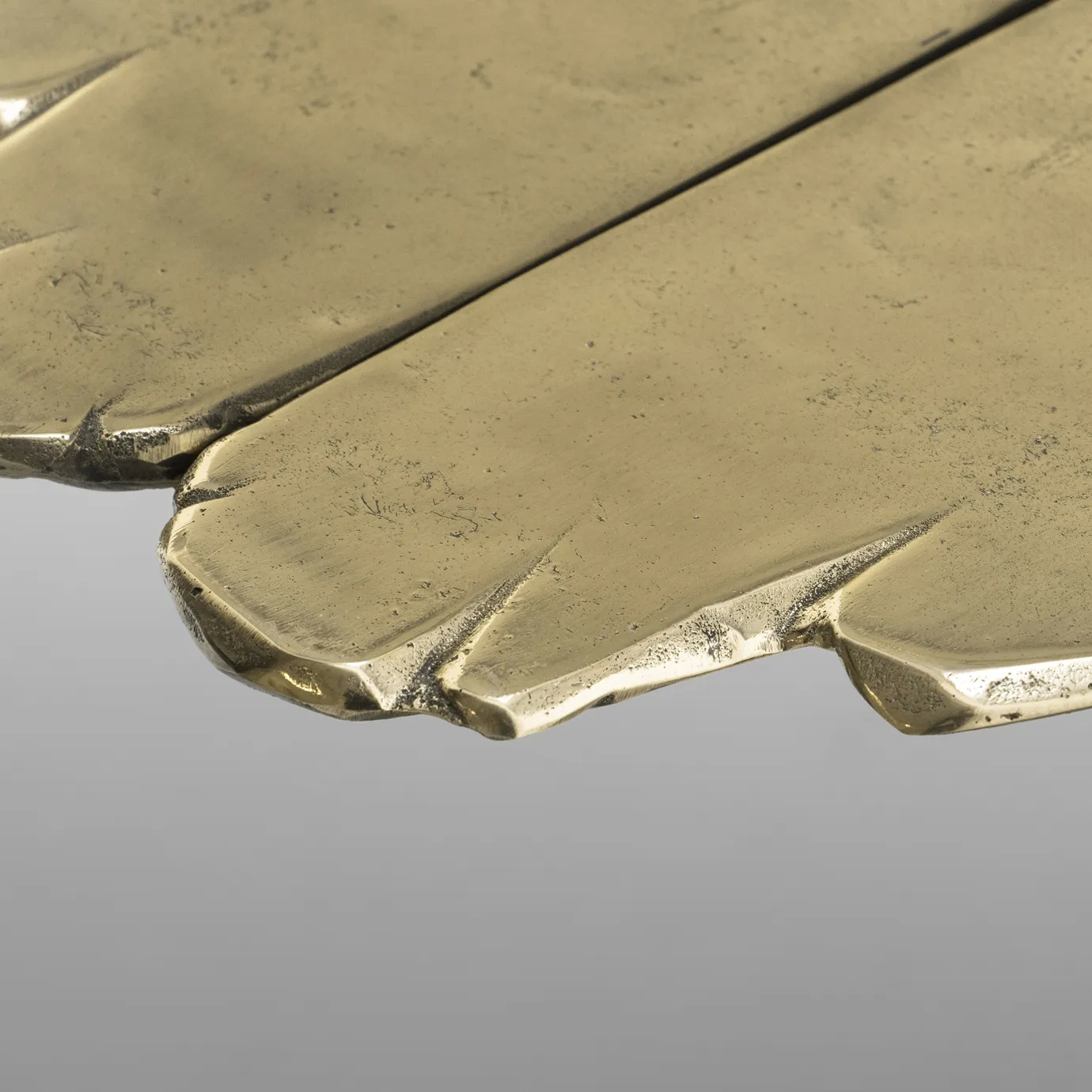 Close-up of Lumiere Console’s gold table edge, showing textured detailing and reflective finish.