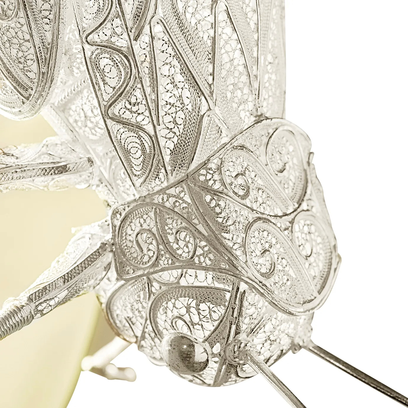 Close-up detail of the grasshopper sconce’s head, showcasing intricate filigree antennae, textured eyes, and antique metal finish for lifelike nature-inspired design