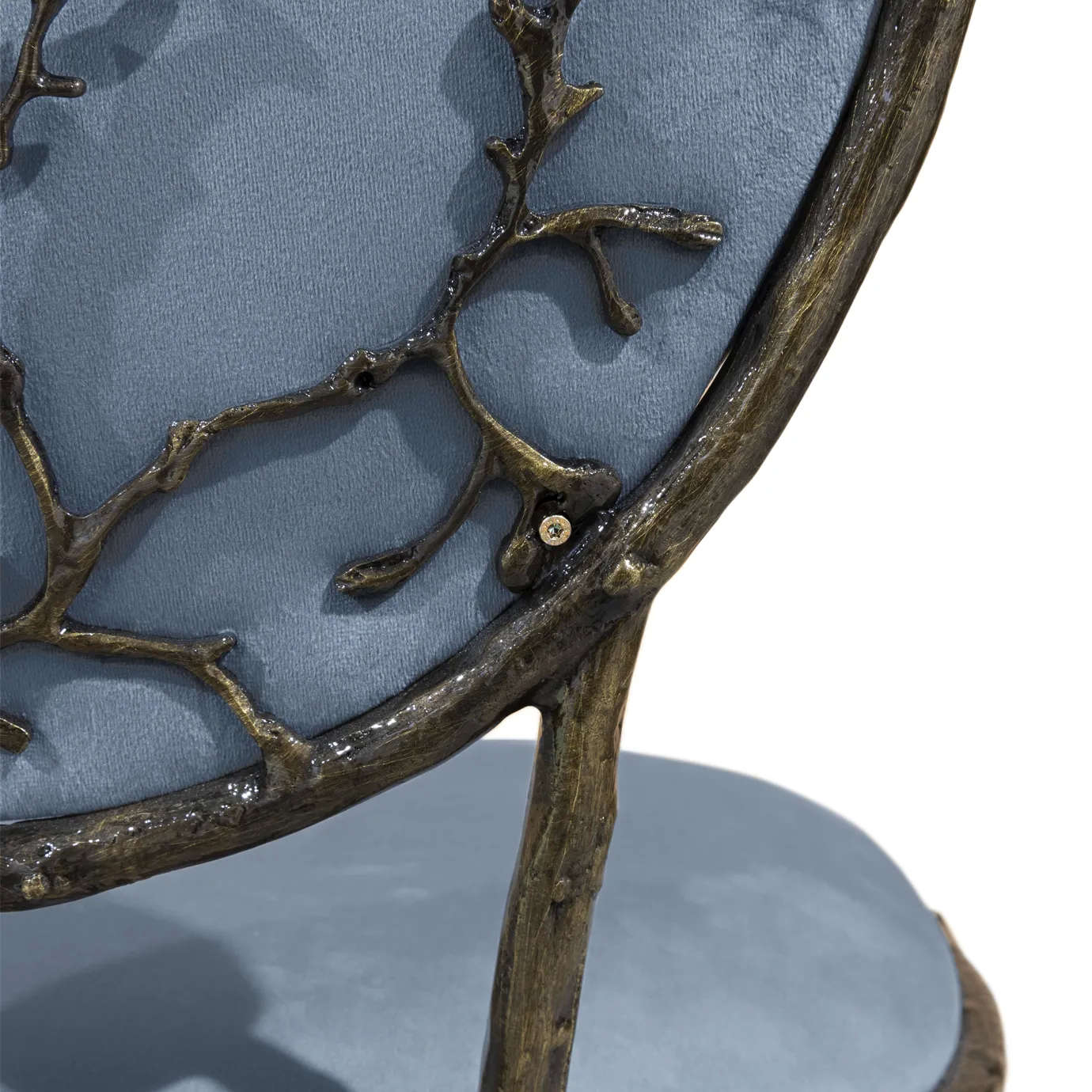 Detailed view of the Enchanted Dining Chair’s elegant aged brass backrest that resembles branches, combining with the blue upholstery.