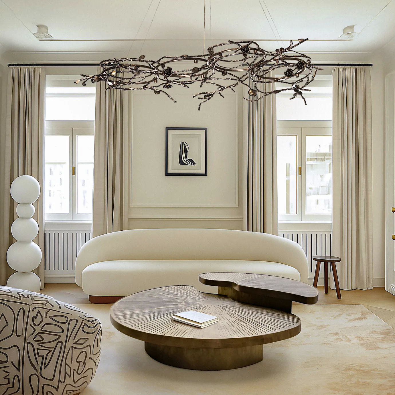 Contemporary living room featuring KOKET’s Rose Oval chandelier in an organic bronze branch design and the sculptural Myth coffee table, a refined modern luxury interior in neutral tones.