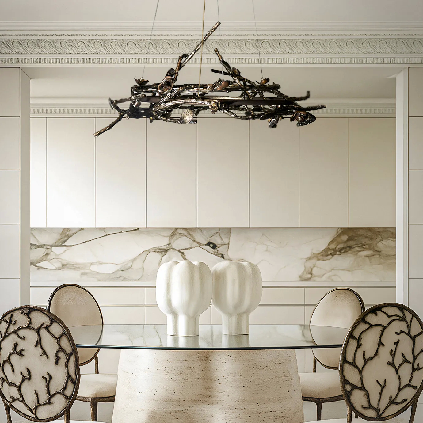 Elegant dining room featuring KOKET’s Rose Round chandelier in bronze metal and Enchanted dining chairs with branch-inspired backs, a modern luxury interior design with marble and neutral tones.