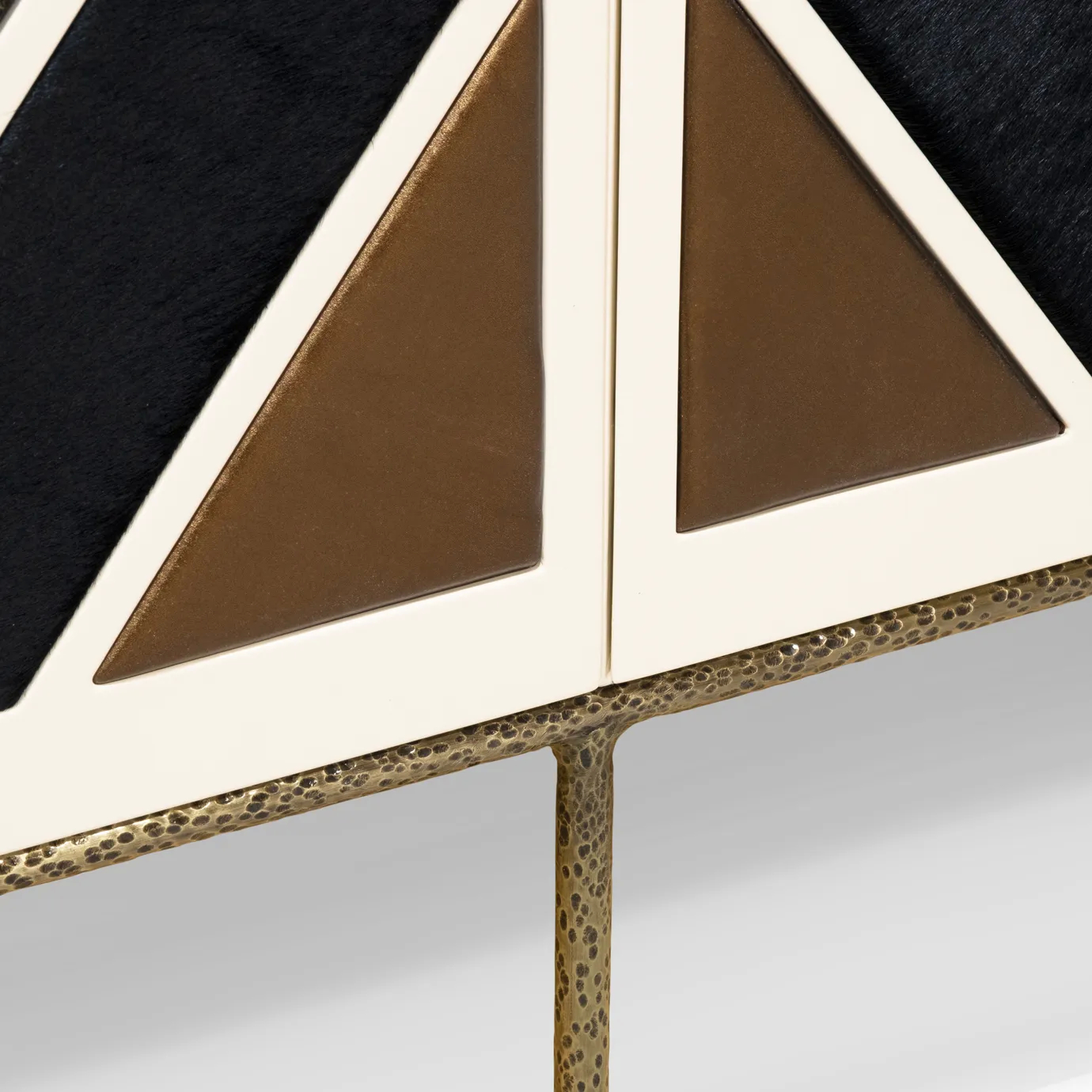 Hammered aged brass base detail on Opium Cream Cabinet showing textured metal finish