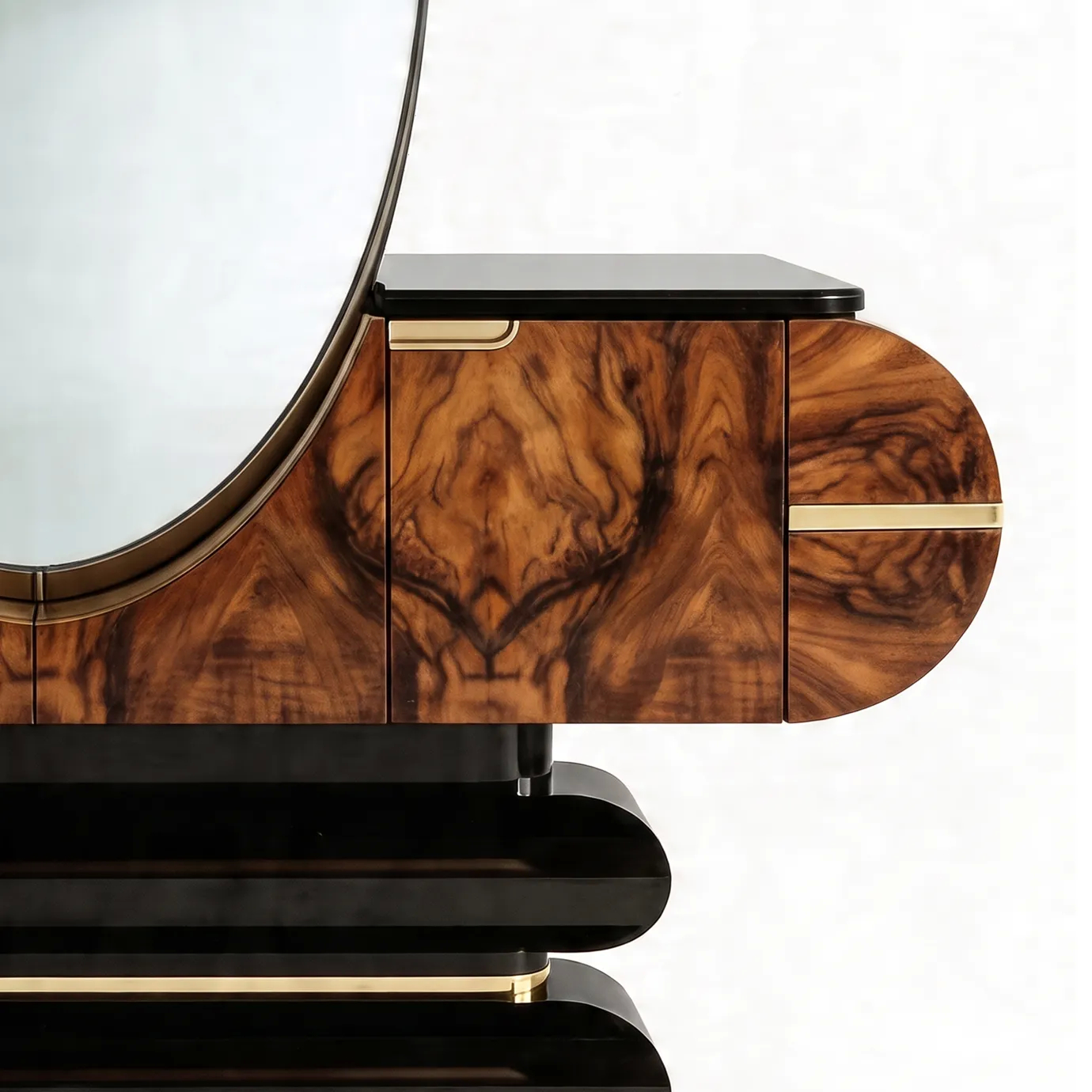 Detail of Elsa console table by KOKET, book-matched walnut burl doors, brass handle and glossy black top beside oval mirror.