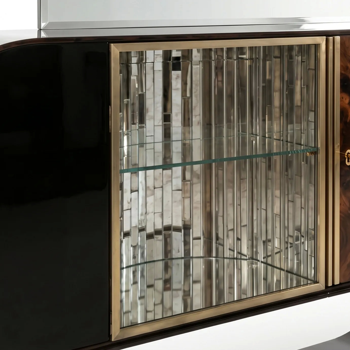 Brass-framed mirror-mosaic door on Florence bar cabinet by KOKET beside the curved black lacquer body, with glass shelves.