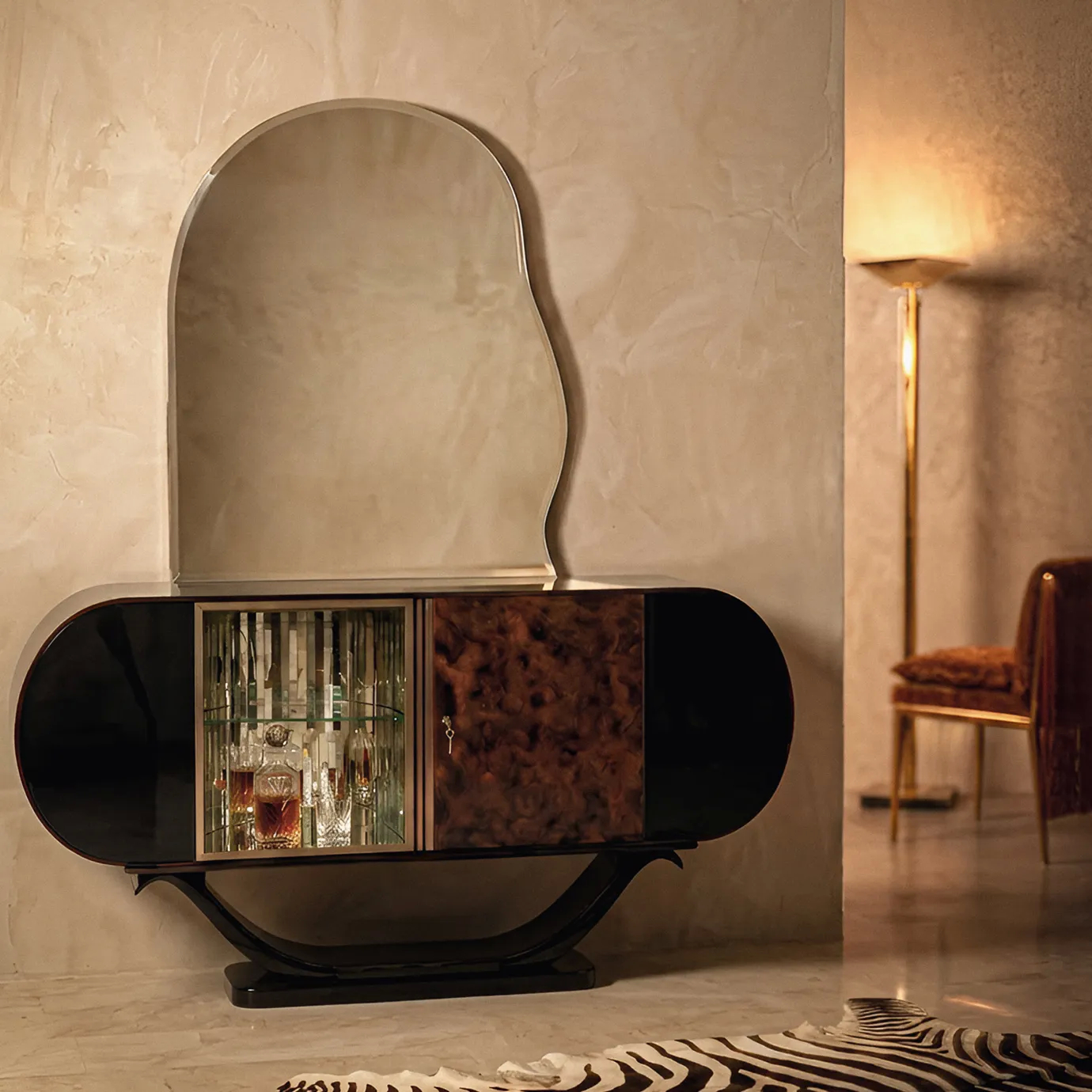 Florence bar cabinet by KOKET in a warm interior with a lit floor lamp and zebra-hide rug, barware glowing inside.