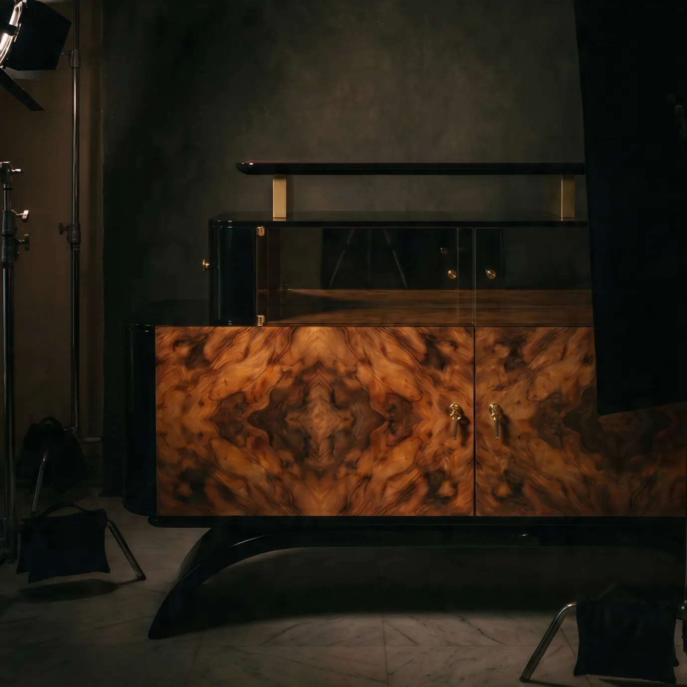 Odette sideboard by KOKET on a studio set with lighting equipment, walnut burl doors and smoked glass display in shadow.