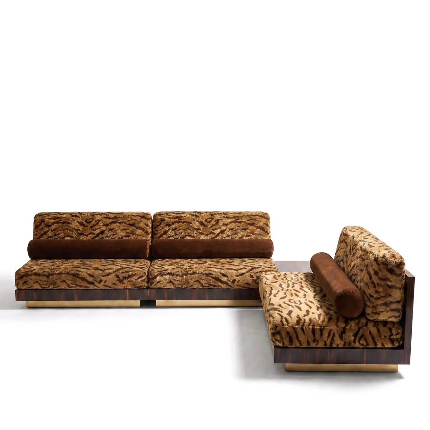 Eileen modular sofa by KOKET in an L-shaped layout, tiger-print velvet with brown bolsters, walnut burl and brass plinths.