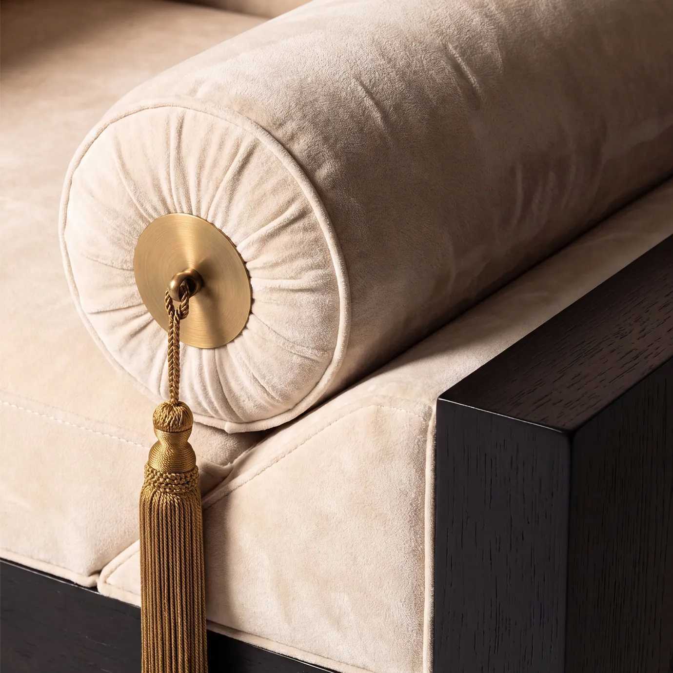 Detail of the polished brass medallion and gold tassel on a cream velvet bolster of Lola armchair by KOKET.