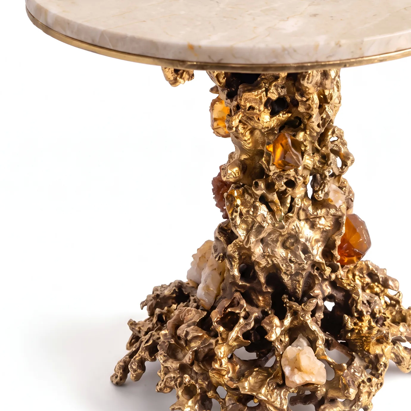 Detail of Empress side table by KOKET, sand-cast brass base set with amber and pale rock crystals below the cream marble top.