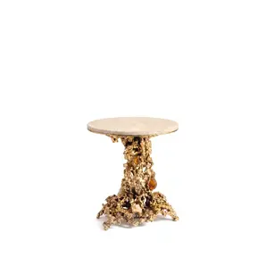 Empress side table by KOKET, front view, cream marble top on a sand-cast brass base with amber and pale rock crystals.