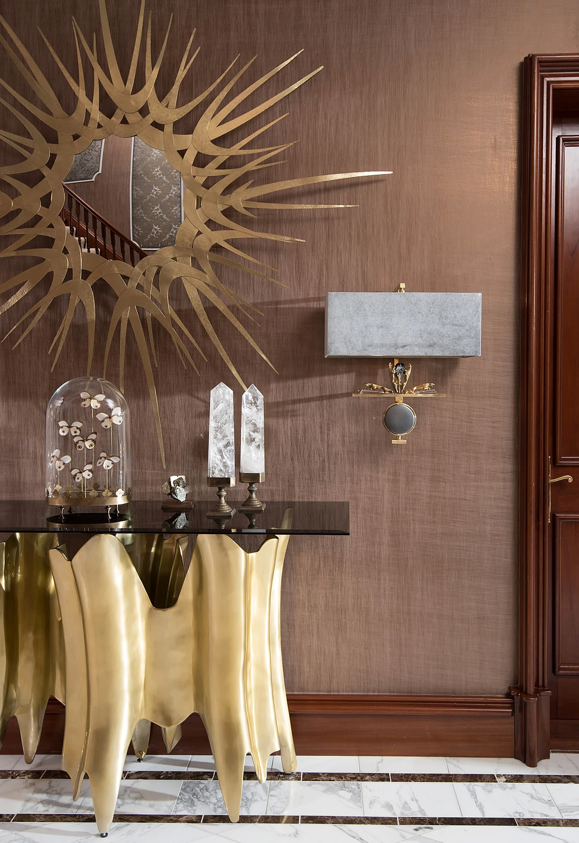 Beechmount Country House: A stunning gold console table with a starburst mirror and elegant wall sconces.