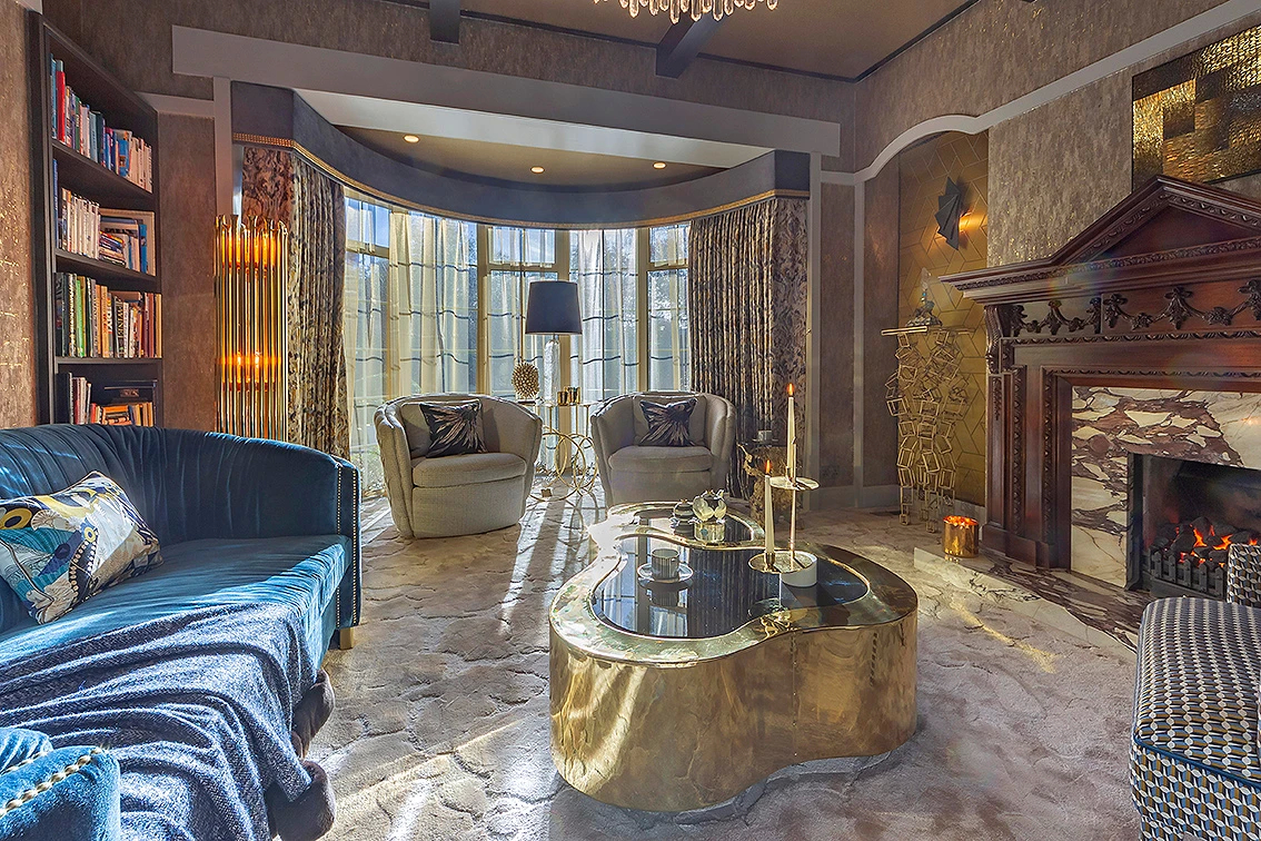 Balmoral's interior showcases a grand living area with an ornate fireplace, a large mirror, and a plush Besame Chair.