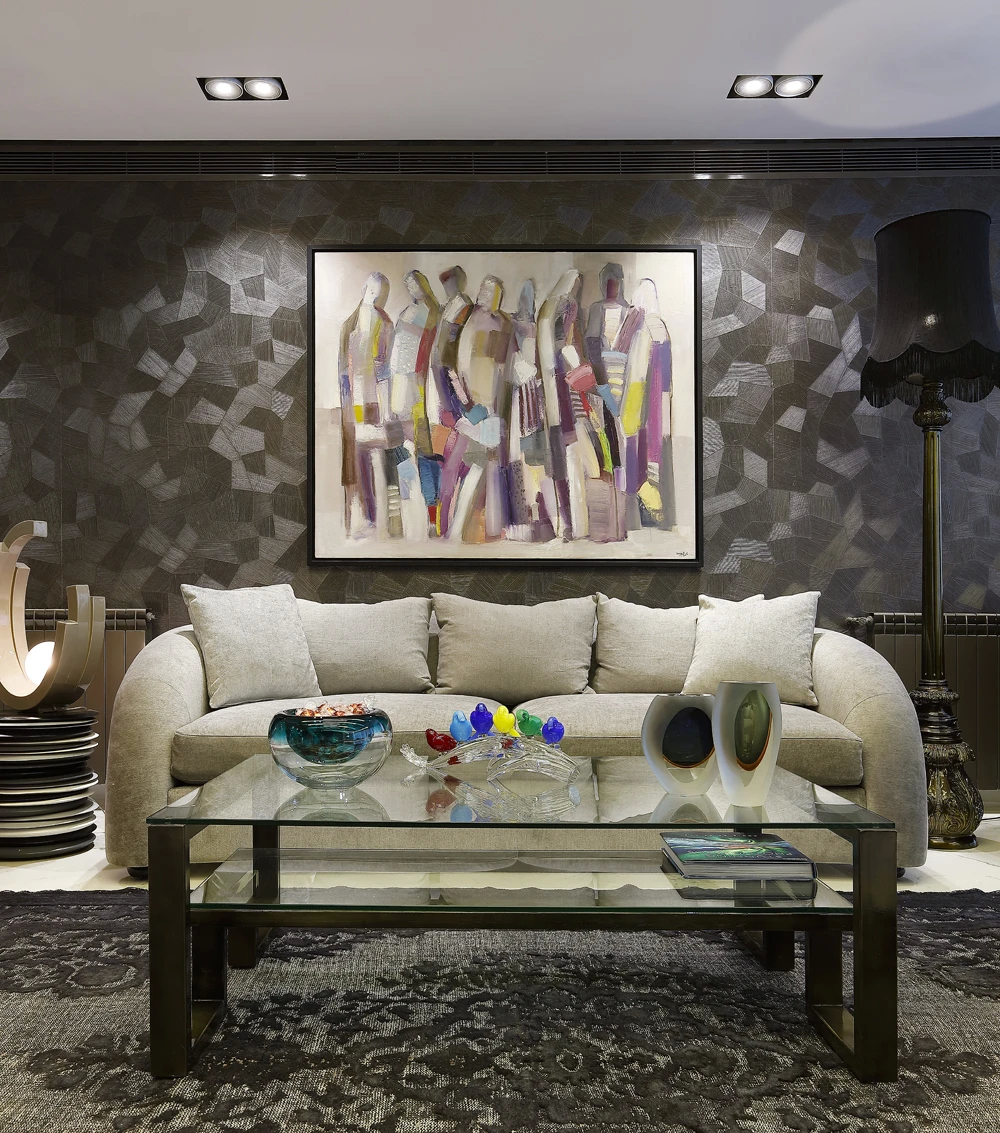 Koket's Residential Apartment features a living room with a light-colored sofa, glass coffee table, and an abstract painting.