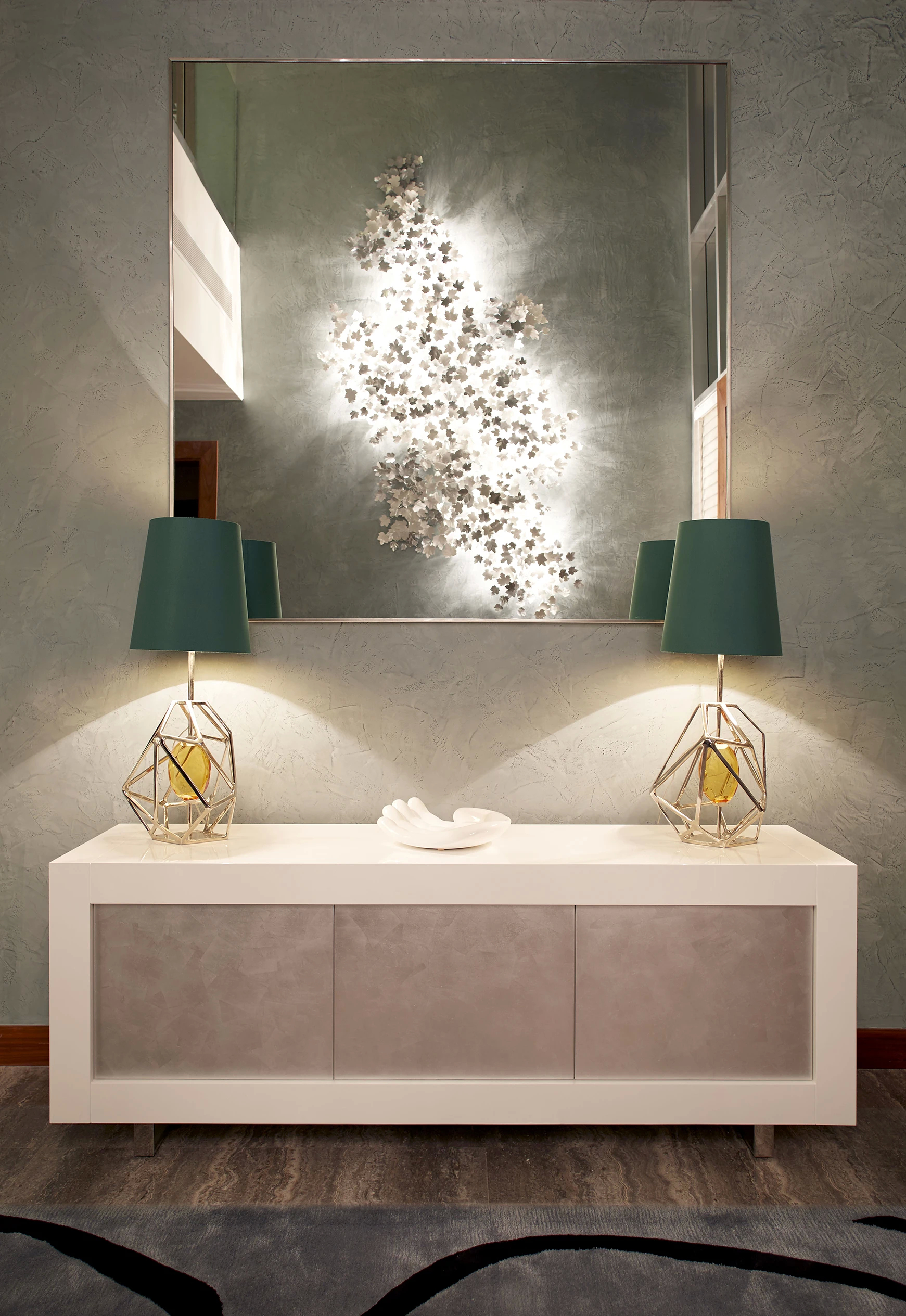 Koket's Emirates Hills Villa features a stone sideboard with two Gem Table Lamps under a large mirror and floral art.
