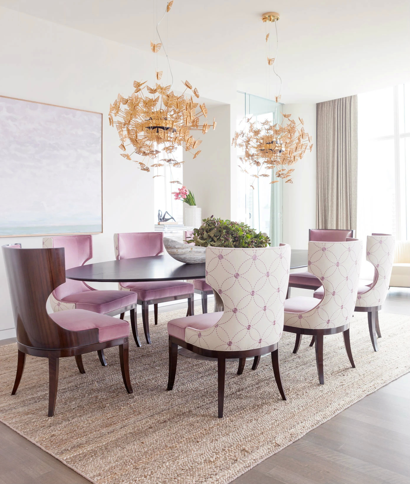 Koket Art Apartment: A dining room with Nymph Chandeliers, a black table, and blush pink and patterned chairs.