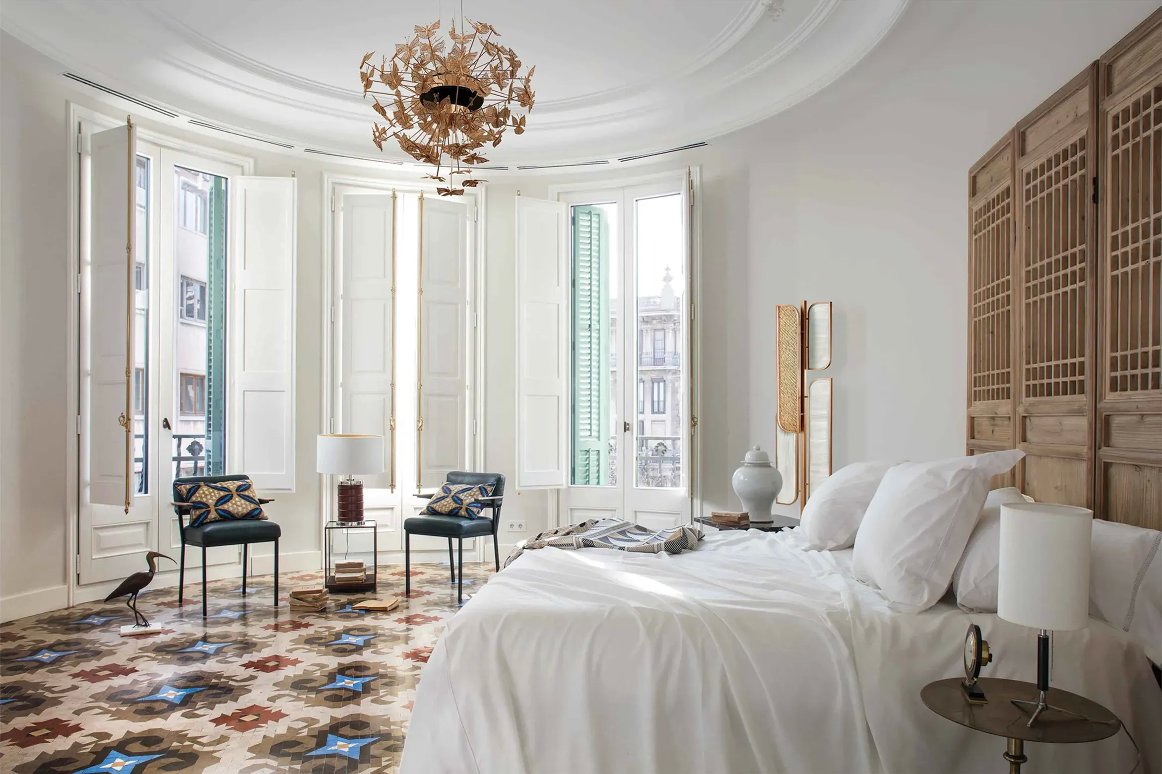 A bedroom with a patterned tile floor, white walls, and a unique chandelier, showcasing Koket's Casa Burés project.