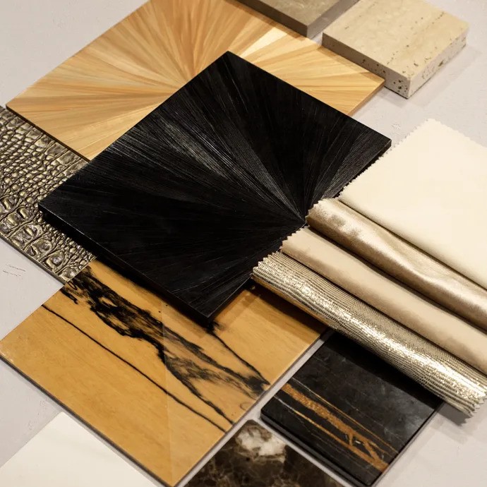 A mood board with assorted material samples. The collection includes wood veneer, marble, textured fabrics, and faux crocodile leather.