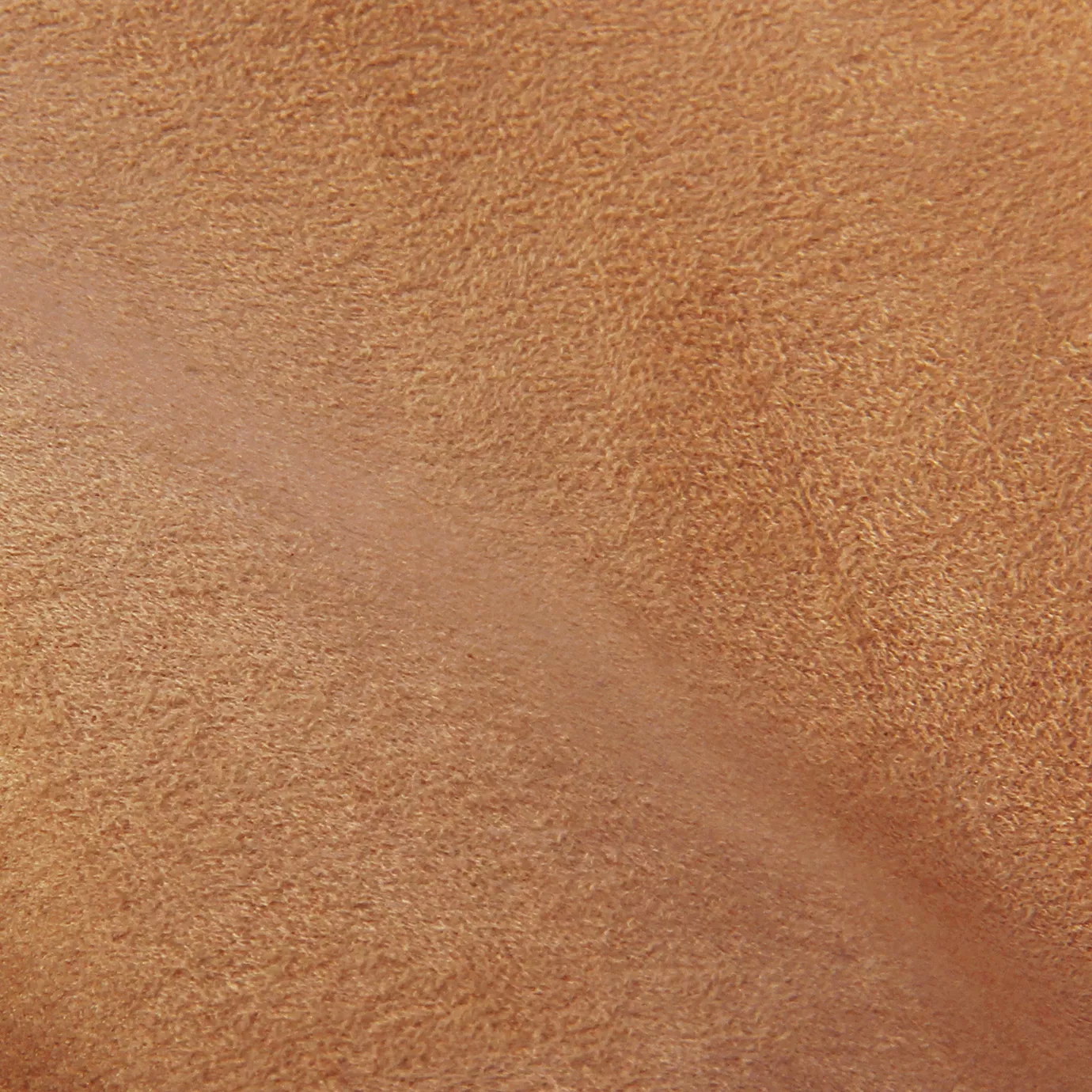 Soft close-up of an Ultra Suede Apricot Nectar fabric swatch in a warm and soft apricot tone, showcasing its delicate texture and a gentle touch that gives it a feeling of comfort and natural elegance.