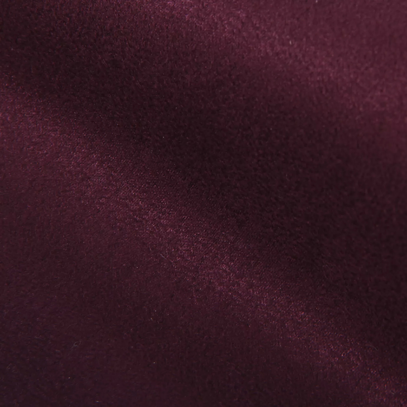 Soft close-up of an Ultra Suede Grape Wine fabric swatch in a rich and sophisticated red wine tone, showcasing its delicate texture and a gentle touch that gives it a feeling of comfort and intense elegance.